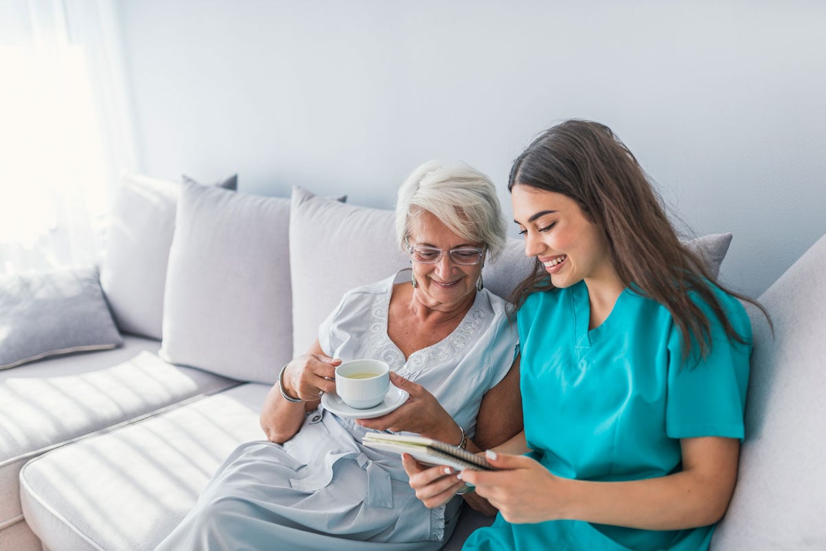 Home care professional reads with elderly woman