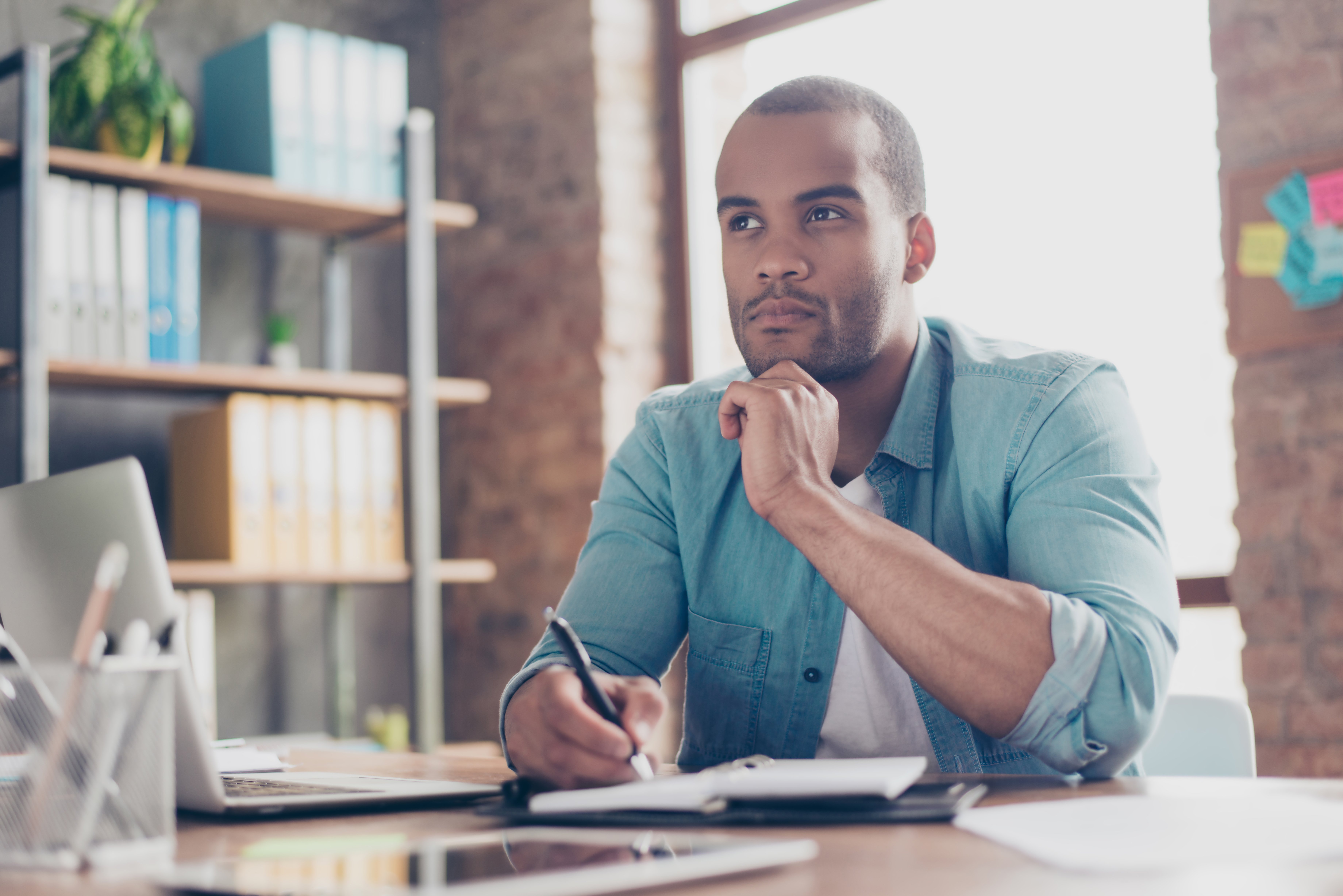 Entrepreneur thinks deeply while writing with pen and paper